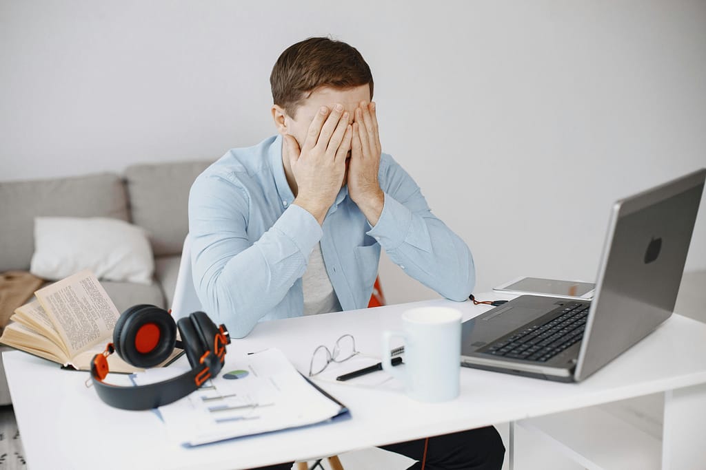 Frustrated man working in a home office, experiencing blurred vision and eye discomfort from prolonged screen use, related to digital eye strain