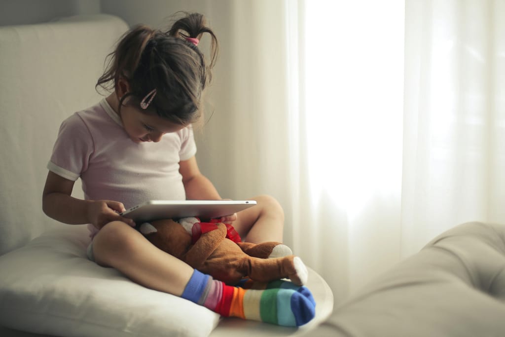 A young child using a tablet in daylight, showing modern screen habits and visual engagement impacting children eye health.