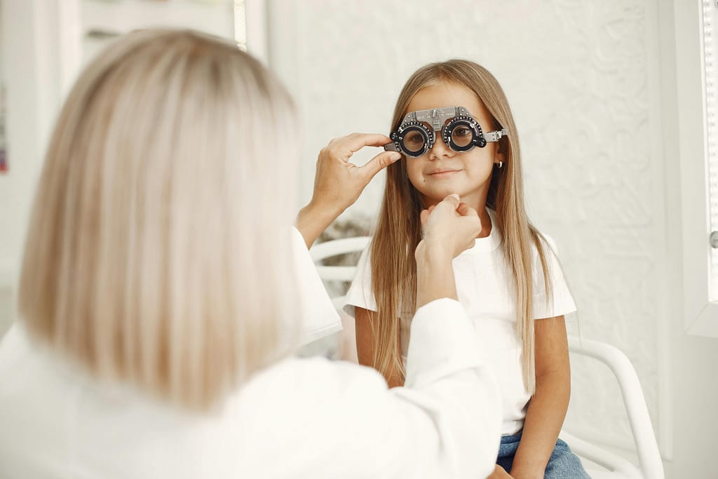 A young child having a pediatric eye exam to determine eye exam frequency.
