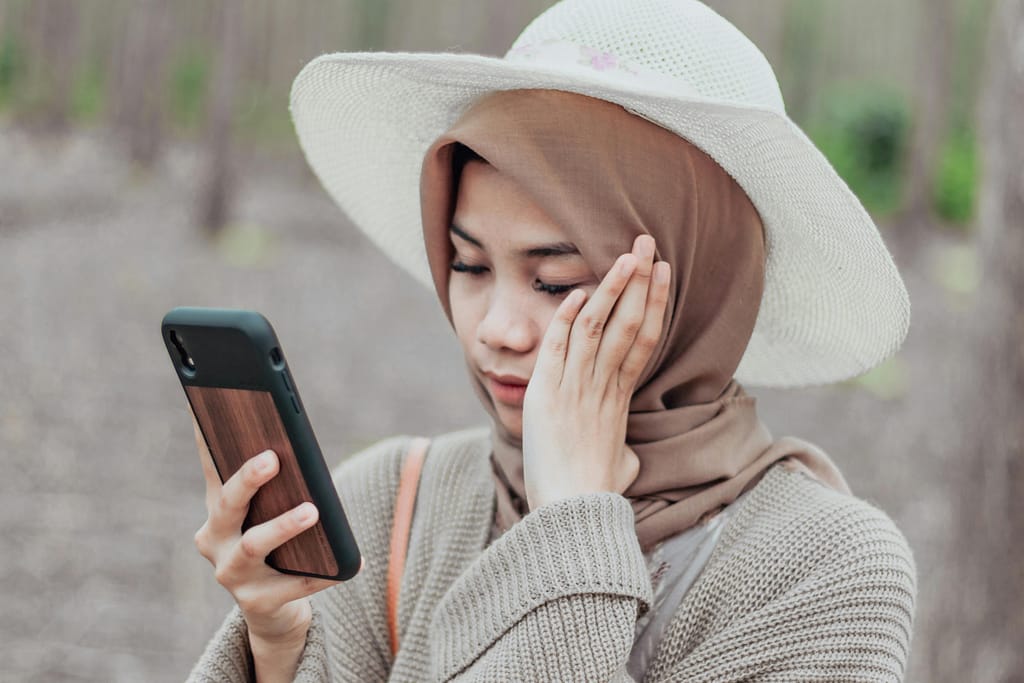 Woman holding a smartphone close to her face due to screen-induced myopia symptoms