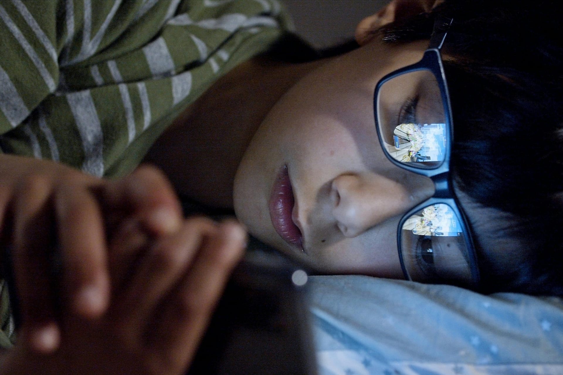 Child looking at a smartphone in dim lighting, symbolizing modern screen exposure and its effects on vision
