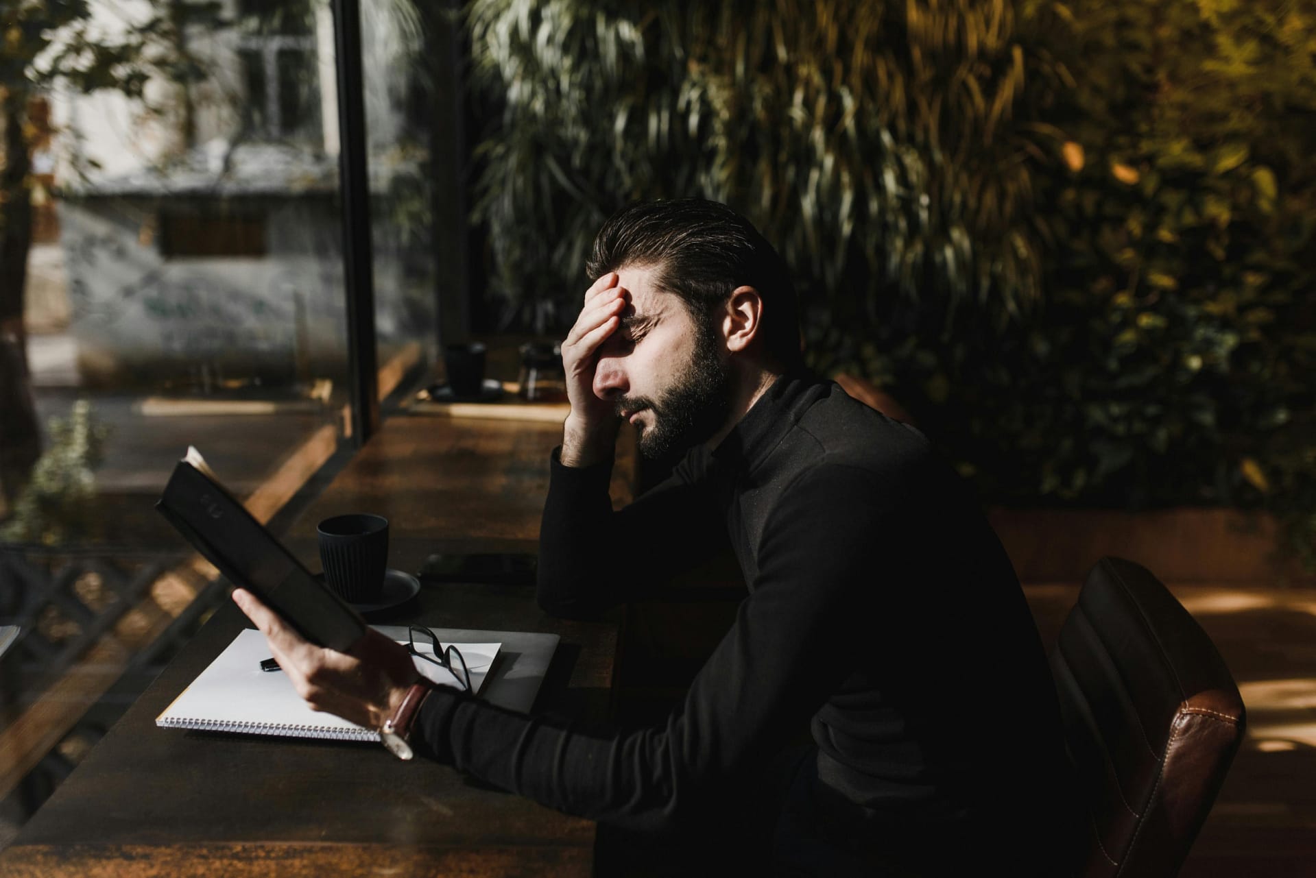 Person holding forehead with eyes closed in natural light, experiencing eye pressure without glaucoma symptoms.